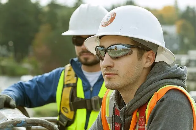 Apprentice electrician in a hard hat and safety glasses at a worksite